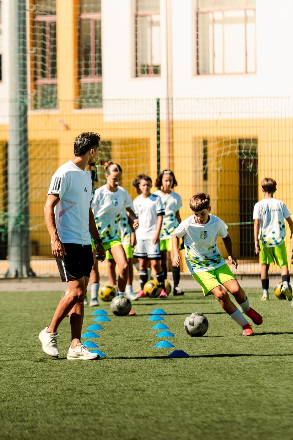 Atleta em exercício de condução de bola com o treinador